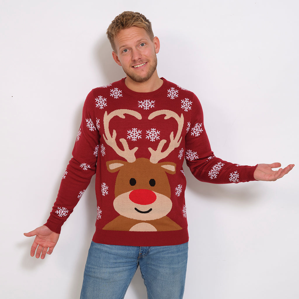 Un homme portant un pull de Noël rouge foncé avec Rudolph et des flocons de neige.